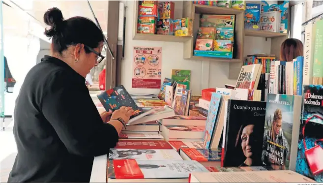  ?? CRISTÓBAL CARRASCO ?? Una lectora ojea un libro en una de las casetas de la feria editorial.