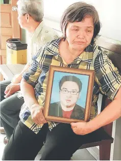  ??  ?? The mother of the murder victim carrying the picture of her son at the court.