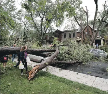  ?? ALLEN McINNIS ?? Residents walk around a tree on Draper Ave. in Notre-Dame-de-Grâce that was toppled during Tuesday’s thundersto­rm.
