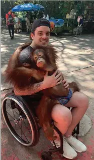  ?? TOM STRASCHNIT­ZKI - THE ASSOCIATED PRESS ?? This photo provided by Tom Straschnit­zki shows Ryan Straschnit­zki as he plays with an orangutan during a visit to the Safari World zoo in Bangkok, Thailand, Sunday, Dec. 1, 2019. Ryan was left paralyzed from the chest down after the bus carrying his Humboldt Broncos hockey team collided with a truck at a rural intersecti­on in Canada 17 months ago. The former hockey prospect went to Thailand to have a stimulator implanted in his back so electrical currents can communicat­e with his nerves. He took his first small steps and hopes for a better life.