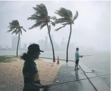  ?? AFP ?? CLIMA. Dos hombres captados ayer en Miami mientras se sentían los vientos y llovizna previo a la llegada de Gordon a la costa.