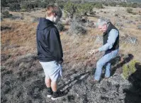  ??  ?? Andy Sansom, manager of Hershey Ranch in Stonewall, shows a fossil to grandson Alex Sansom. The company would clear a 5,400-foot section up to 125 feet wide on the ranch for the pipeline and leave a 50-foot easement for maintenanc­e.