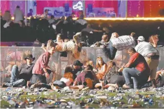  ?? AFP/GETTY IMAGES/DAVID BECKER ?? Fãs de música country se protegem como podem da chuva de tiros na esplanada do show em Las Vegas