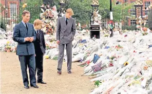  ?? ?? The then Prince of Wales and his sons Princes Harry and William view the host of floral tributes to their mother, Diana, Princess of Wales, at Kensington Palace, her former London residence, on Sept 5, 1997