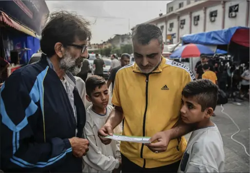  ?? Picture: Abed Zagout/ Anadolu via Getty Images ?? Palestinia­ns read leaflets dropped by the Israeli Army demanding urgent informatio­n on Israeli hostages and Hamas, in Khan Yunis, Gaza