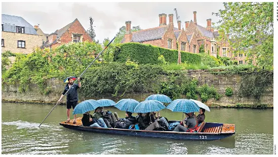  ?? ?? Tourists shelter under umbrellas during a punt on the River Cam in Cambridge yesterday
