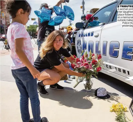  ??  ?? TRIBUTES A woman and her daughter place flowers at a memorial outside Dallas Police HQ yesterday