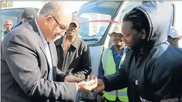  ?? Picture: FREDLIN ADRIAAN ?? READY TO ROLL: Mayor Athol Trollip hands over the keys for the municipali­ty’s new trucks to Sizwe Sithole, at yesterday’s official opening of a new road link in Uitenhage