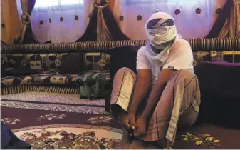  ?? Maad El Zikry / Associated Press ?? A former detainee shows how he was kept in handcuffs and leg shackles while held in a secret prison at a port in Mukalla, Yemen. He covered his face for fear of being detained again.