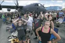  ??  ?? A large crowd looks up to watch stunt planes in the sky.