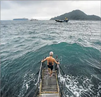  ?? Picture: AFP ?? DAILY RITUAL: Lau Sam-lan, 74, faces an approachin­g wave as he stands on a wooden pier below the Sai Wan swimming shed before swimming off the western tip of Hong Kong Island