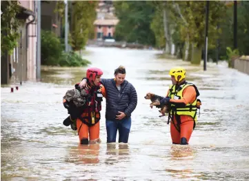  ?? — AFP photos ?? Firefighte­rs helps a resident with a dog following heavy rains that saw rivers bursting banks in Trebes, near Carcassone, southern France.