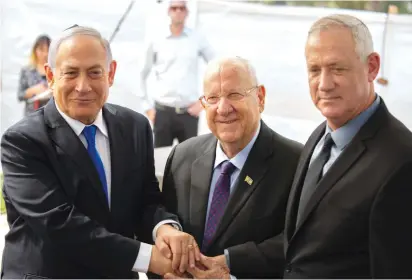  ?? (Esty Dziubov/TPS) ?? PRIME MINISTER Benjamin Netanyahu, President Reuven Rivlin and Blue and White leader Benny Gantz join hands at Thursday’s memorial ceremony for Shimon Peres on Mount Herzl.