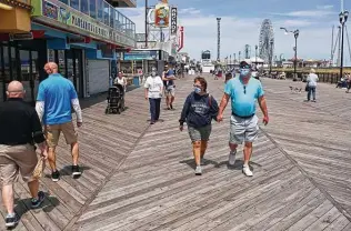  ?? Yana Paskova / Getty Images ?? People traverse the boardwalk after the state reopened beaches in Seaside Heights, N.J. Gov. Phil Murphy said he’s ready to bring back social distancing rules if needed.