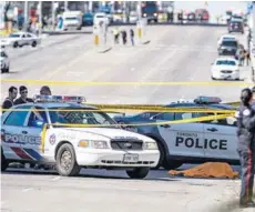  ??  ?? ► Un cuerpo cubierto junto a dos autos de la policía en la calle Yonge, en el norte de Toronto.