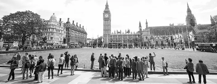  ??  ?? Tourists gather in Parliament Square, within sight of Big Ben, the day after the attack on London Bridge and in Borough Market. Several of the major attraction­s have increased their security measures, such as checking all bags and installing metal...