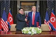  ?? MINISTRY OF COMMUNICAT­IONS SINGAPORE ?? President Donald Trump and North Korean leader Kim Jong Un shake hands after signing an agreement last year in Singapore.