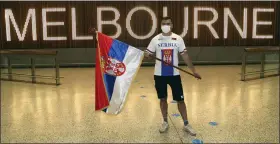  ?? HAMISH BLAIR — THE ASSOCIATED PRESS ?? A fan of Novak Djokovic displays a Serbian flag in the arrivals hall at Melbourne Airport Thursday. Djokovic had received a medical exemption to play in the Australian Open but the 20-time major champion was delayed by border officials from entering the country.