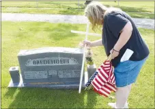  ?? Westside Eagle Observer/MIKE ECKELS ?? Jeanelle Simpson plants a white cross on the headstone of local Air Force veteran D.K Bredehoeft May 16 as she joined members of the Decatur Veterans Committee and the Howard-Parrish VFW Post 9834 in raising flags at the Decatur Cemetery. The crosses and flags were erected to commemorat­e Memorial Day on May 25.