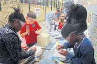  ??  ?? Some of the 100-plus participan­ts take part in open and free stone-sculpting workshops carving their part of “Cornerston­e.”