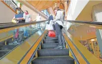  ?? AP PHOTO/ DAVID ZALUBOWSKI ?? Holiday shoppers keep their distance and wear face masks while riding an escalator to battle the spread of the new coronaviru­s Dec. 8 in Park Meadows Mall in Lone Tree, Colo.