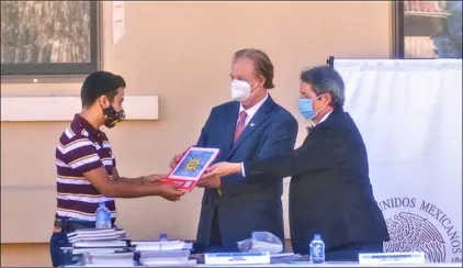  ?? PHOTO VINCENT OSUNA ?? Adrien Lopez, 13, of Calexico, (left) receives a book from Dr. Miguel Meza Estrada and Tarcisio Navarrete (far right) during a books donation ceremony on Tuesday in Calexico.