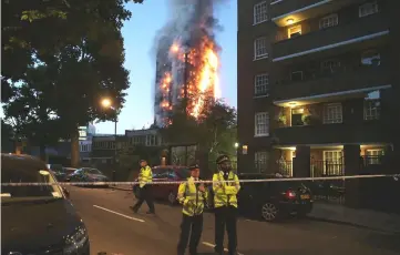  ?? — AFP photo ?? File photo shows police manning a security cordon as a huge fire engulfs the Grenfell Tower in west London.