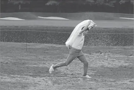  ?? Tony Gutierrez Associated Press ?? IT’S EASY TO SEE why play was suspended for the day, with this situation at the 18th hole at Baltusrol. Officials say they will try to complete the PGA today, but there is a good chance for more rain at the New Jersey course, making a Monday finish...