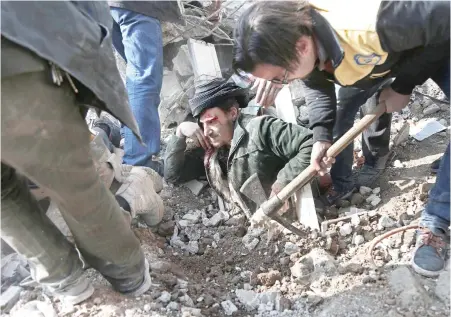  ??  ?? Volunteers from the Syrian civil defense group White Helmets dig a man out of the rubble following an airstrike on Saqba, in the besieged opposition-held Eastern Ghouta, near Damascus, on Tuesday. (AFP)