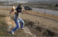  ?? (Reuters) ?? WHO IS paying him? A Palestinia­n throws a molotov cocktail at an Israeli jeep.