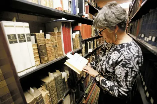  ??  ?? Margaret Van Dyk, director of library services at the Santa Fe University of Art and Design, looks through some of the rare books April 18 at the Fogelson Library.