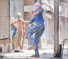  ??  ?? A masked protester throws pieces of bricks and stones towards Indian police officers during a clash on the occasion of the death anniversar­y of Burhan Wani in downtown Srinagar. — Reuters photo