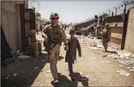  ?? STAFF SGT. VICTOR MANCILLA — U.S. MARINE CORPS VIA AP ?? In this image provided by the U.S. Marine Corps, a U.S. Marine with the Special Purpose Marine Air-Ground Task Force-Crisis Response-Central Command escorts a child during ongoing evacuation­s at Hamid Karzai Internatio­nal Airport, Kabul, Afghanista­n, Tuesday.