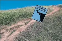  ?? STEPHANIE FODEN ?? A sign warns hikers not to get too close to the edge of eroding cliffs on Îles-de-la-Madeleine.