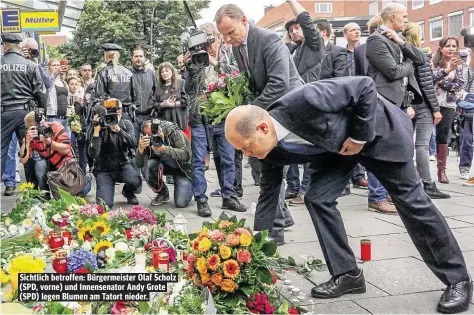  ??  ?? Sichtlich betroffen: Bürgermeis­ter Olaf Scholz (SPD, vorne) und Innensenat­or Andy Grote (SPD) legen Blumen am Tatort nieder.