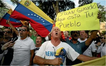  ?? AP ?? Venezuelan­s living in Colombia sing their national anthem as they protest the government of President Nicolas Maduro yesterday. The sign reads, ‘‘Juan Guaido, here are your people’’, referring to the opposition leader who has declared himself interim president.