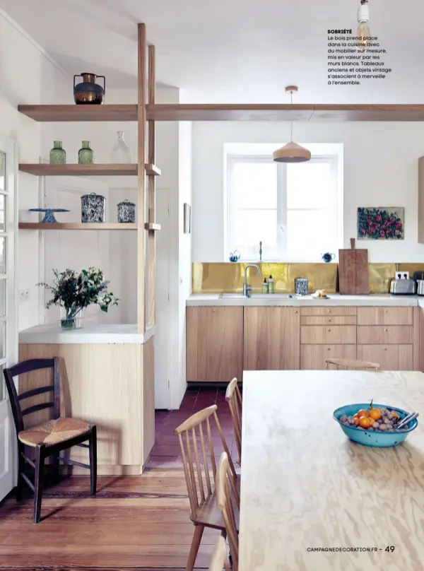  ??  ?? Sobriété Le bois prend place dans la cuisine avec du mobilier sur mesure, mis en valeur par les murs blancs. Tableaux anciens et objets vintage s’associent à merveille à l’ensemble.