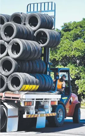  ?? Picture: ALIX SWEENEY ?? LOADS OF WORK: A front- end loader builds a stack of safety barrier tyres aboard a truck as the Townsville 400 site is disassembl­ed.