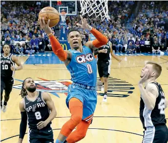  ?? —AP ?? Oklahoma City Thunder guard Russell Westbrook (Centre) shoots between San Antonio Spurs guard Patty Mills (left) and forward Davis Bertans during the second half of an NBA game in Oklahoma City on Saturday.