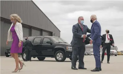  ?? ALEX WONG/GETTY IMAGES ?? Brian McPartlin (middle) shakes hands with Democratic presidenti­al nominee Joe Biden on Thursday at General Mitchell Internatio­nal Airport in Milwaukee. Biden’s wife, Jill, is at left.