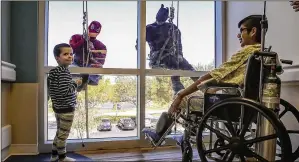  ?? PHOTOS BY DAMON HIGGINS /PALM BEACH POST ?? Mason Mueller, 4, (left) of Wellington and Angel Aguilar, 13, of West Palm Beach watch Tuesday as Spider-Man and Batman rappel outside Palms West Hospital.