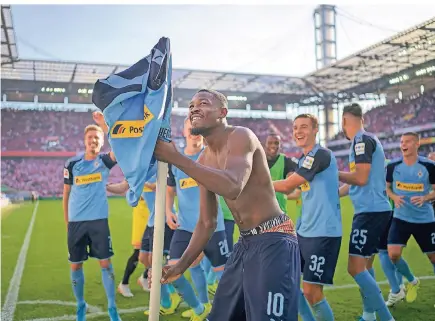  ?? FOTO: SVEN SIMON ?? Schlussjub­el vor den Gladbacher Fans im Kölner Stadion: Marcus Thuram hat sein Borussia-Trikot über die Eckfahne gezogen, hinter ihm tanzen seine Mannschaft­skollegen.