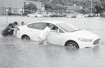  ?? Melissa Phillip / Houston Chronicle ?? Joseph Chipello, right, and others push a car toward dry pavement Tuesday on North Braeswood near Hillcroft. Most employers don’t fire employees who can’t make it to work because of dangerous conditions.