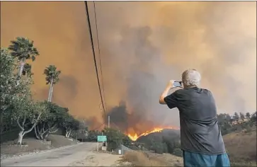  ?? Genaro Molina Los Angeles Times ?? A RESIDENT shoots video of the Woolsey fire threatenin­g homes in Malibu in November. California leaders want to help electricit­y providers pay for wildfires, a critical move to head off another utility bankruptcy.