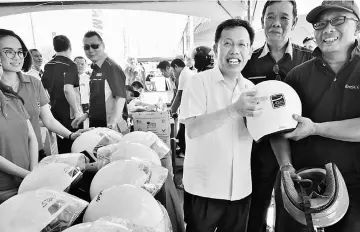  ??  ?? Dr Sim (third right) distribute­s a crash helmet to a motorcycli­st.