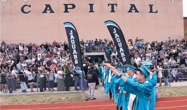  ?? PHOTOS BY CLYDE MUELLER/THE NEW MEXICAN ?? Capital High School seniors walk onto the football field at the school for their graduation ceremony last month.