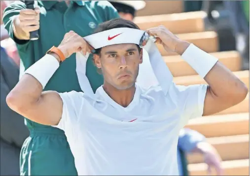  ??  ?? GUERRERO. Rafa Nadal se coloca su clásica bandana antes de jugar contra Sela ayer en la primera ronda de Wimbledon.