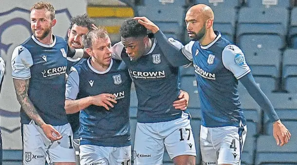  ??  ?? HEARTS-BREAKER: Jonathan Afolabi celebrates with his Dundee team-mates after sealing the victory over Hearts from the penalty spot.