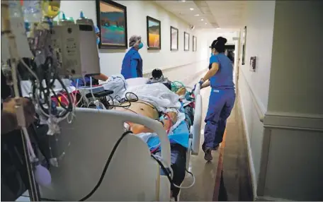  ?? Nelvin C. Cepeda San Diego Union-Tribune ?? A COVID-19 PATIENT is wheeled to the ICU at the Jacobs Medical Center at UC San Diego Health in La Jolla. Healthcare leaders say they’re mystified by the Trump administra­tion’s unwillingn­ess to commit to extending emergency orders that start expiring next month.