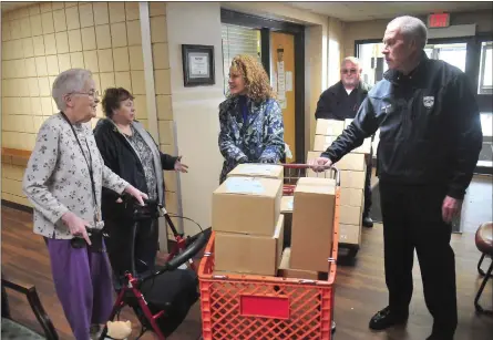  ?? Ernest A. Brown photo ?? Woonsocket
Mayor Lisa Baldelli-Hunt, center, joined
by Police Chief Thomas Oates, right, and George
Lahousse, deliver boxes of food for senior residents at Waterview Apartments in
Woonsocket Tuesday. They delivered 100
boxes there as well as 150 at Park View Manor, 150 at Crepeau Court and 130 at St. Germain
Manor.
